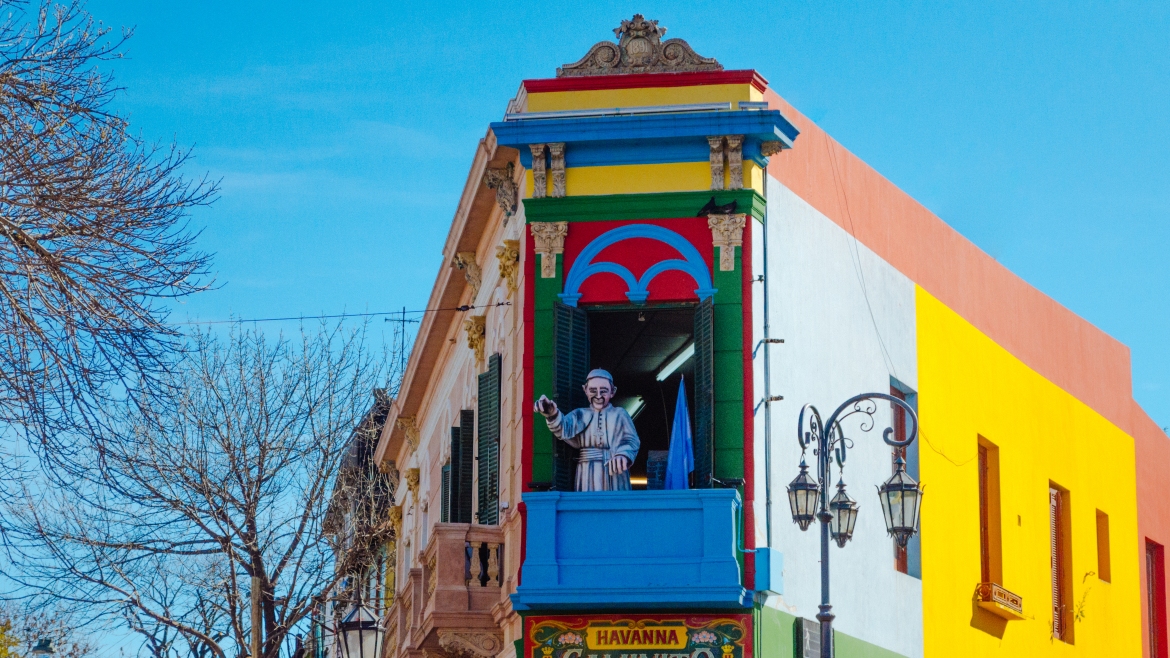 The famous colorful streets of El Caminito with the famous statue of Pope Francis waving at the crowd.