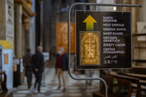 A multilingual sign in Turin, Italy, with an arrow pointing towards the Santa Sindone, or Holy Shroud, attracting tourists and pilgrims.