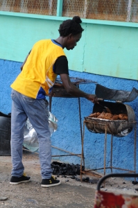 A Jamaican man is cooking the well known Jerk Chicken on a old rusty grill near Port Antonio in Jamaica