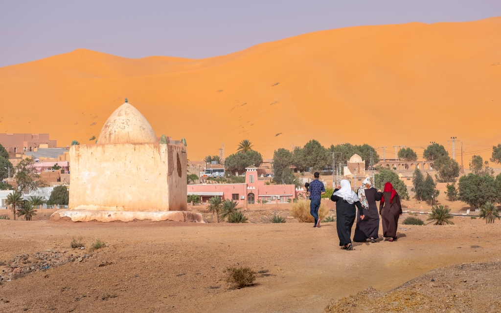 TAGHIT, ALGERIA - APRIL 20, 2018:Local Arabs approaching marabout tomb near Taghit town in oasis of Sahara desert