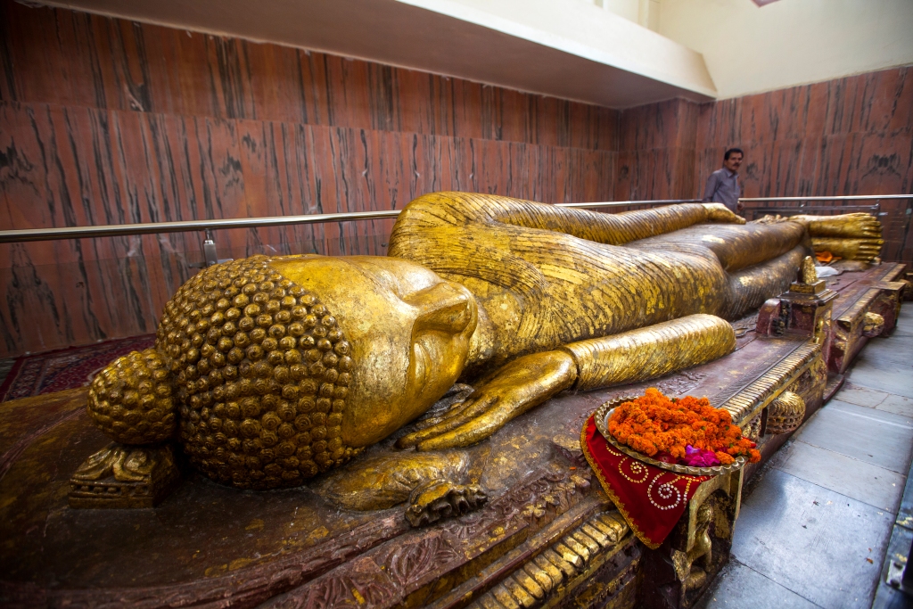 Kushinagar, Uttar Pradesh, India - March 20, 2013: The reclining Nirvana statue of the Buddha inside the Parinirvana Stupa.