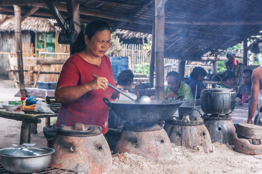 Woman cook on fire on the street market in island of Negros, Philippines