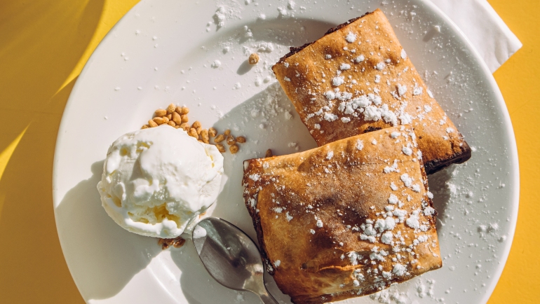 Pastel maltés de dátiles llamado Imqaret servido con helado en el plato.