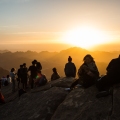 Peregrinos y turistas mirando el amanecer en la cima del Monte Sinaí