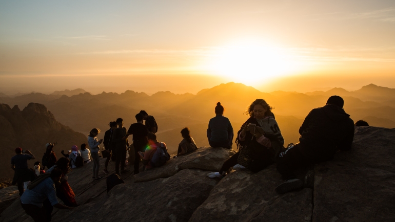 Peregrinos y turistas mirando el amanecer en la cima del Monte Sinaí