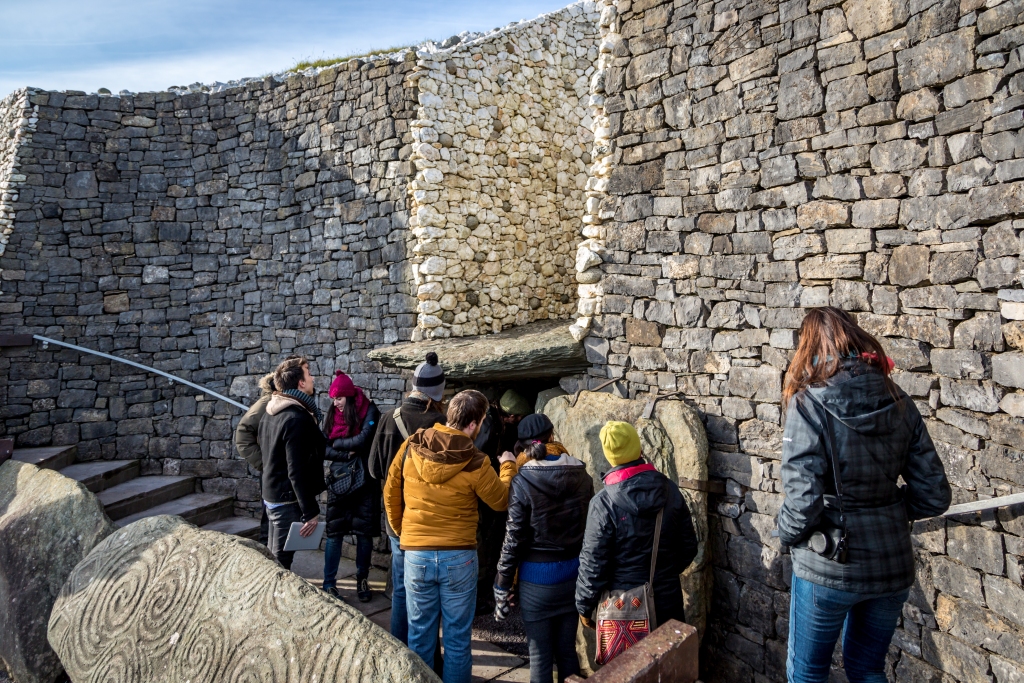 Tourists entering in the Newgrange Stone Age Passage Tomb in a blue sky day, winter time