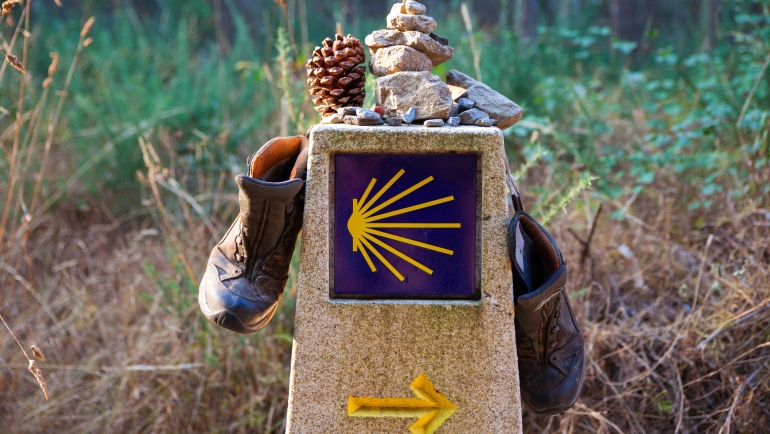 Hiking boot and stone on the stone sign, symbol of the Camino de Santiago