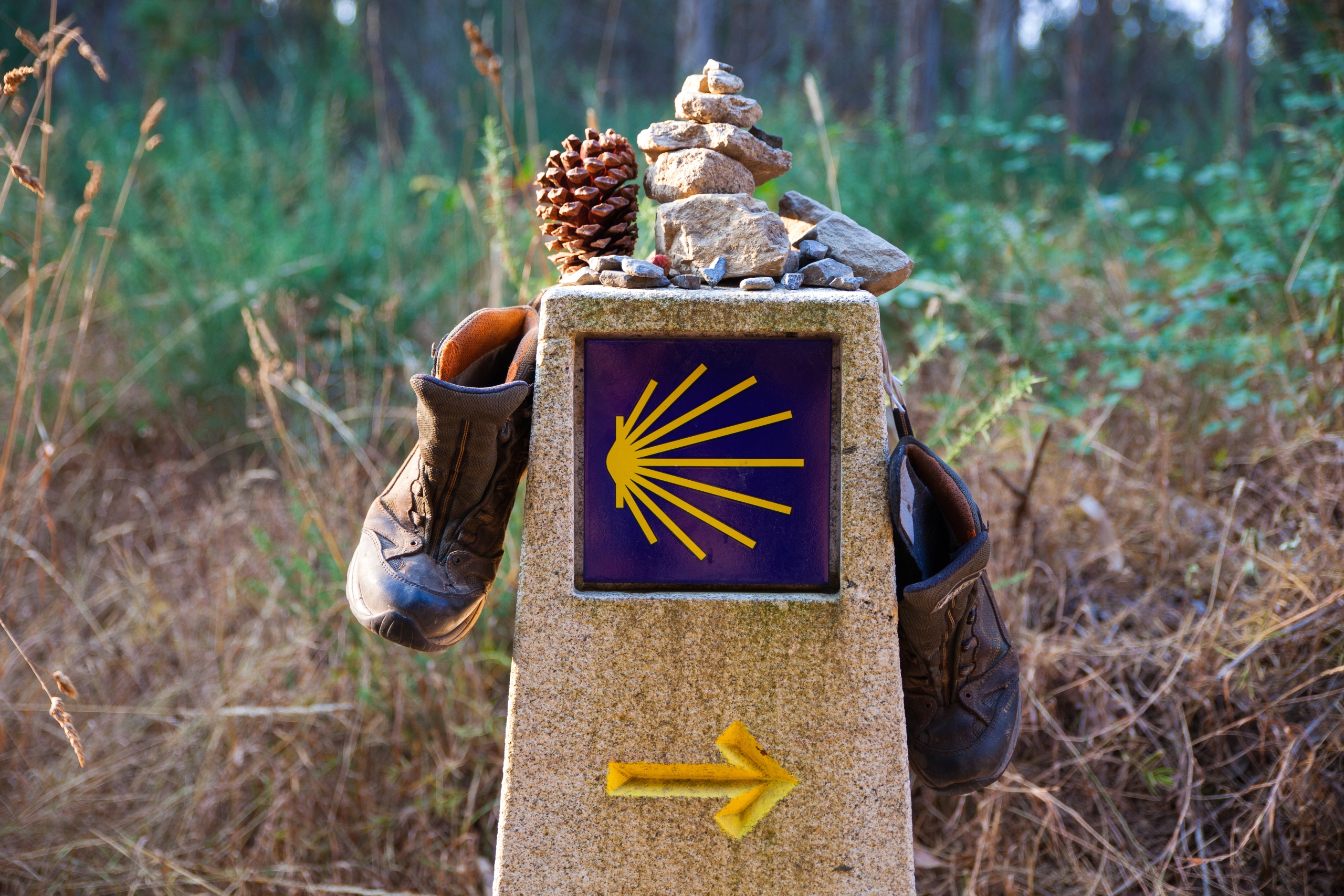 Hiking boot and stone on the stone sign, symbol of the Camino de Santiago