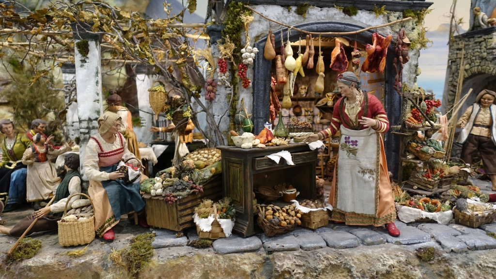 Scenes of daily life in an old Neapolitan nativity scene with figures of food, fruit and vegetable vendors.