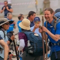 smiling pilgrims holding walking sticks celebrate their achievement after completing the camino de santiago in santiago de compostela