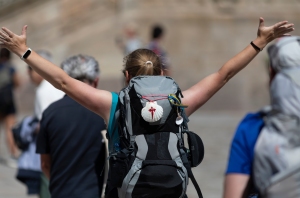 A pilgrim celebrates her arrival at the Plaza do Obradoiro in Santiago de Compostela after completing the Camino de Santiago.