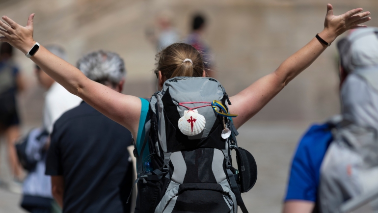 A pilgrim celebrates her arrival at the Plaza do Obradoiro in Santiago de Compostela after completing the Camino de Santiago.
