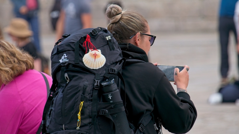 pilgrim woman capturing smartphone photos near the cathedral of santiago de compostela