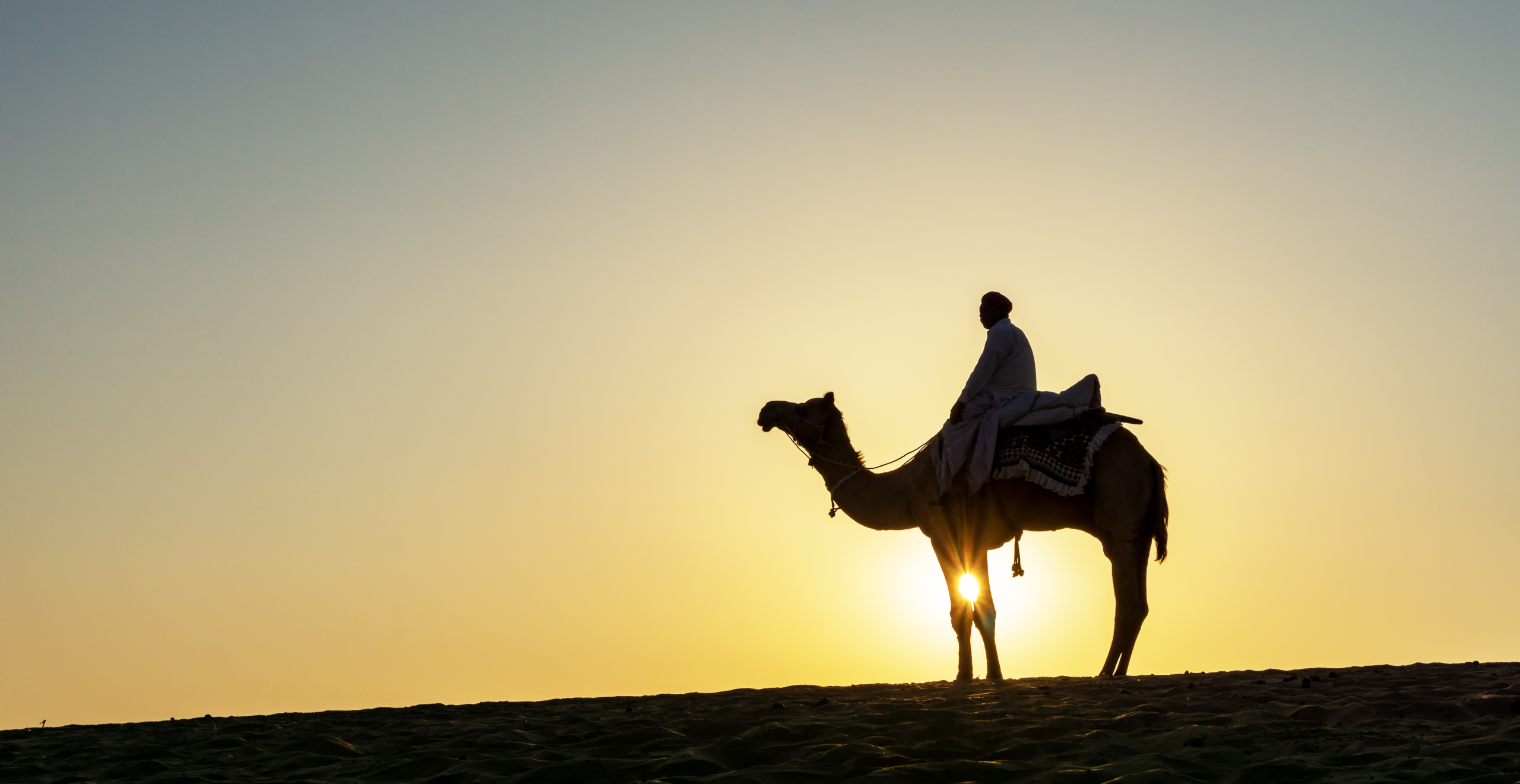 Silhouette,Of,Indian,Man,And,Camel,During,Sunrise,At,Thar