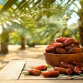 Dried date fruits with a date palm background.
