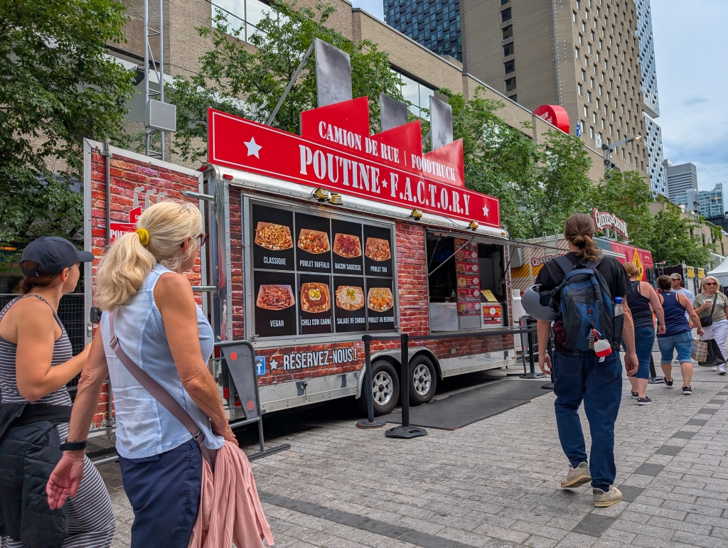 People walking past a poutine food truck at a busy Quebec street festival