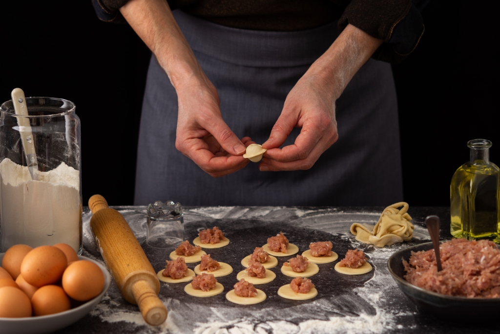 A man cooks traditional pelmeni filled with meat.