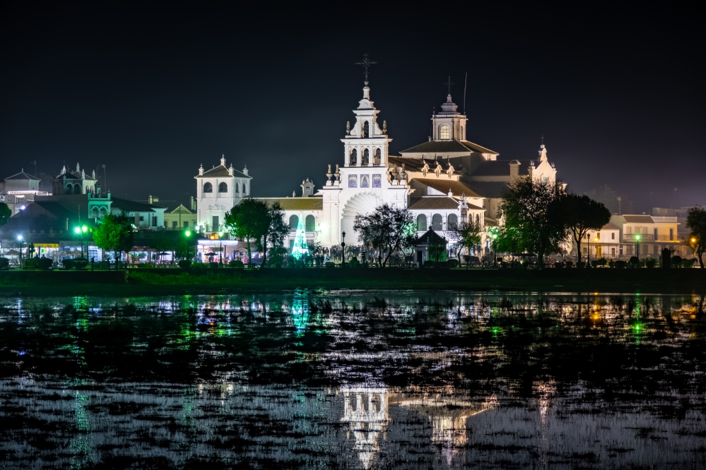Long shot of El Rocio church and town at night with lake and reflections