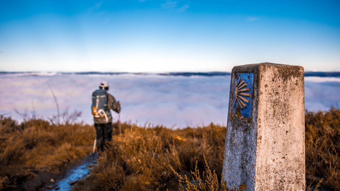 Pilgrim walking on the Camino de Santiago, above a sea of ​​clouds in the middle of nature