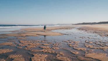 Lone woman walking along the low tide beach in Portugal, on the Portuguese Way to Santiago