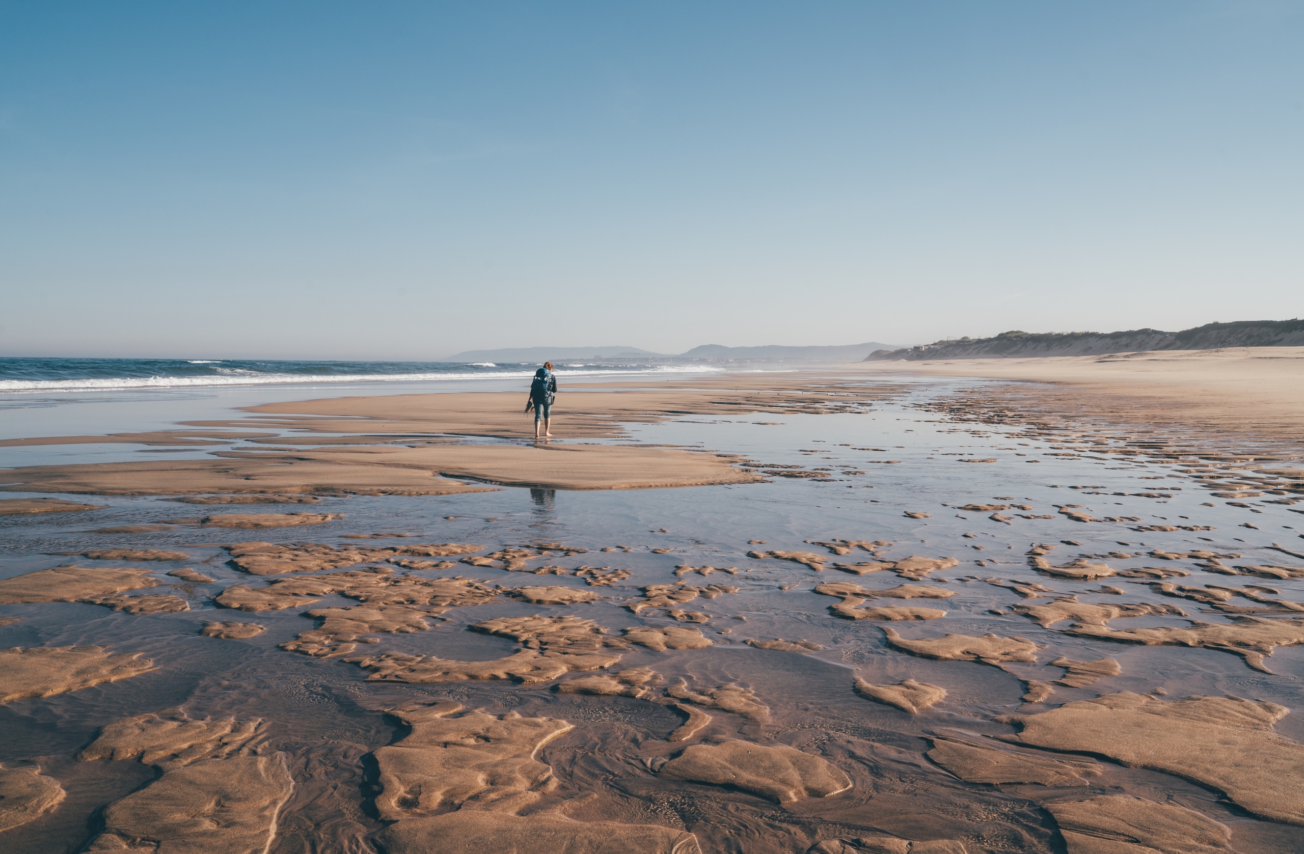Lone woman walking along the low tide beach in Portugal, on the Portuguese Way to Santiago