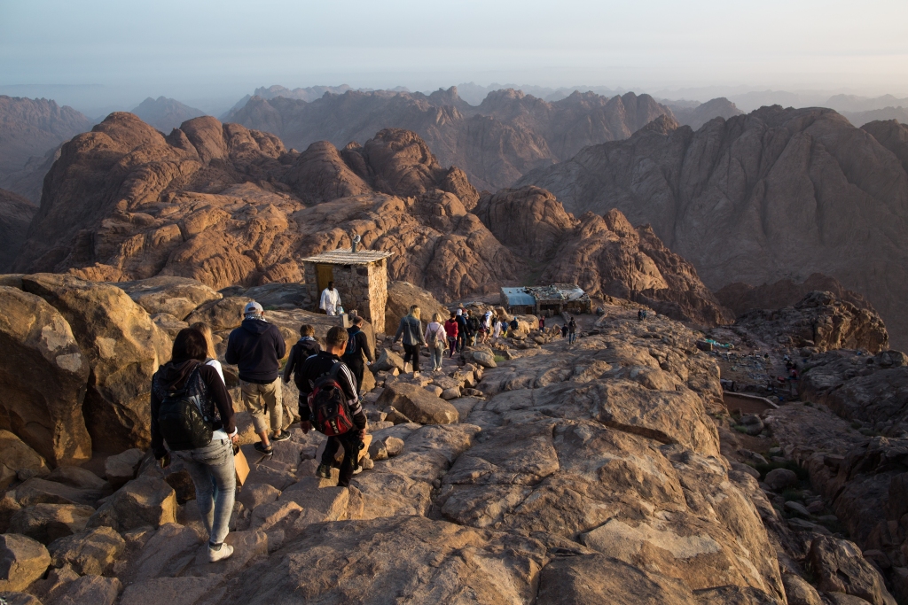 Group of tourists walking along the rocky path from Mount Sinai at dawn