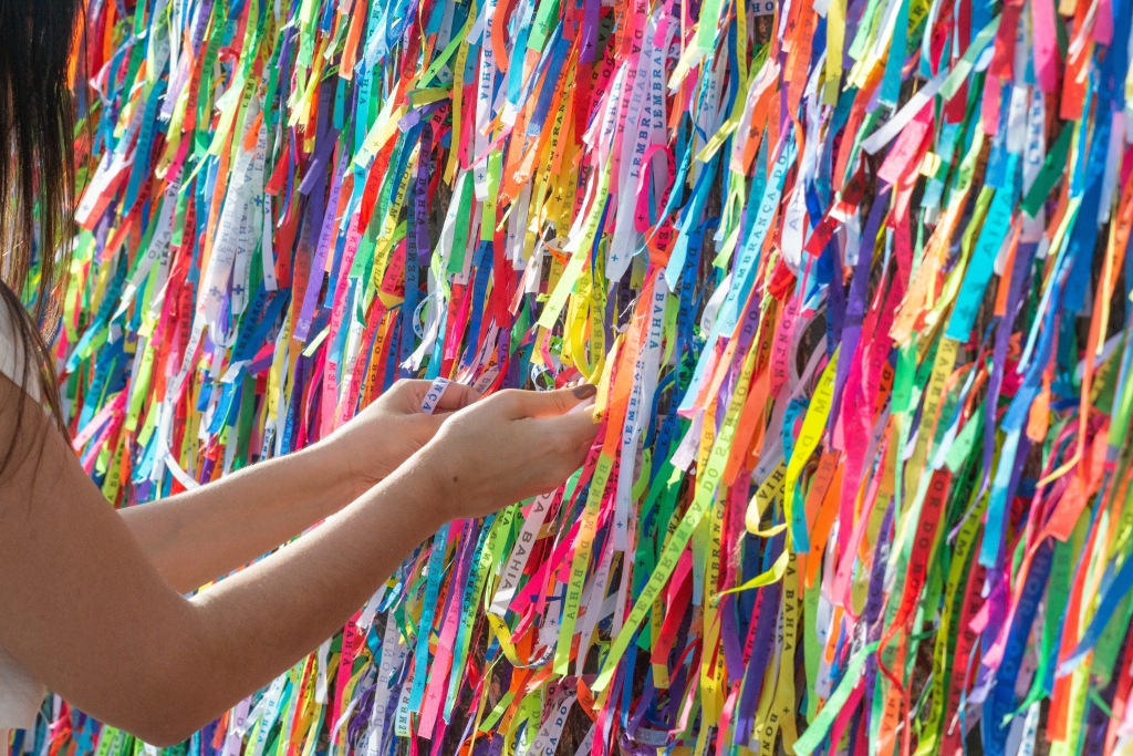 Tourists tying colorful souvenir ribbons on the door of the Senhor do Bonfim church