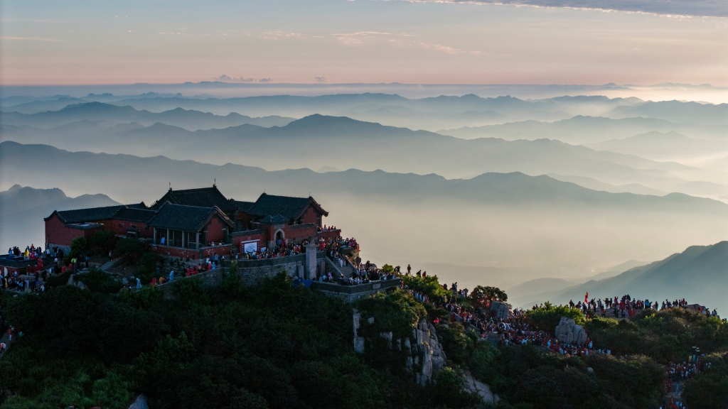 Tourists watch the sunrise from the summit of Mount Taishan