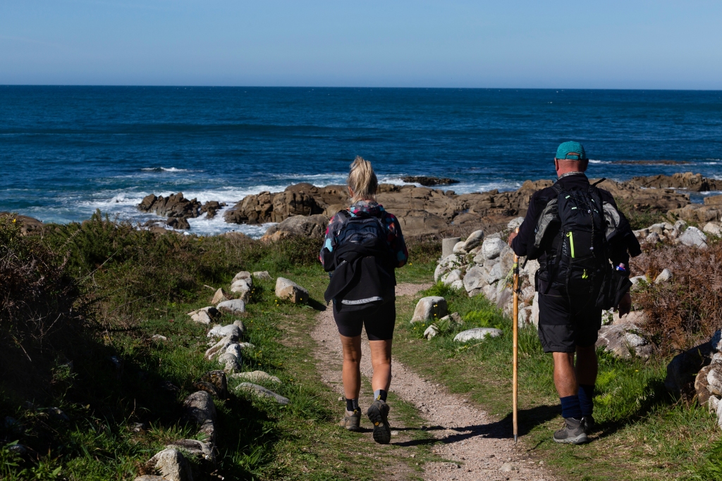 Two pilgrims walk along the Portuguese Way of St. James along the coast in A Guarda