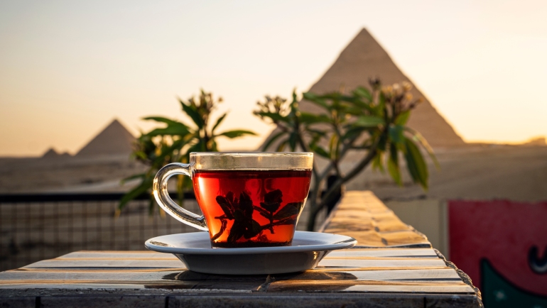 A cup of hibiscus tea in front of the pyramids of Giza