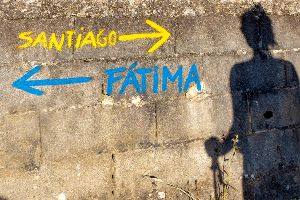 Shadow of a pilgrim facing the arrows that mark the Camino de Santiago and the pilgrimage to Fátima. Only Fabrizio / Shutterstock.com