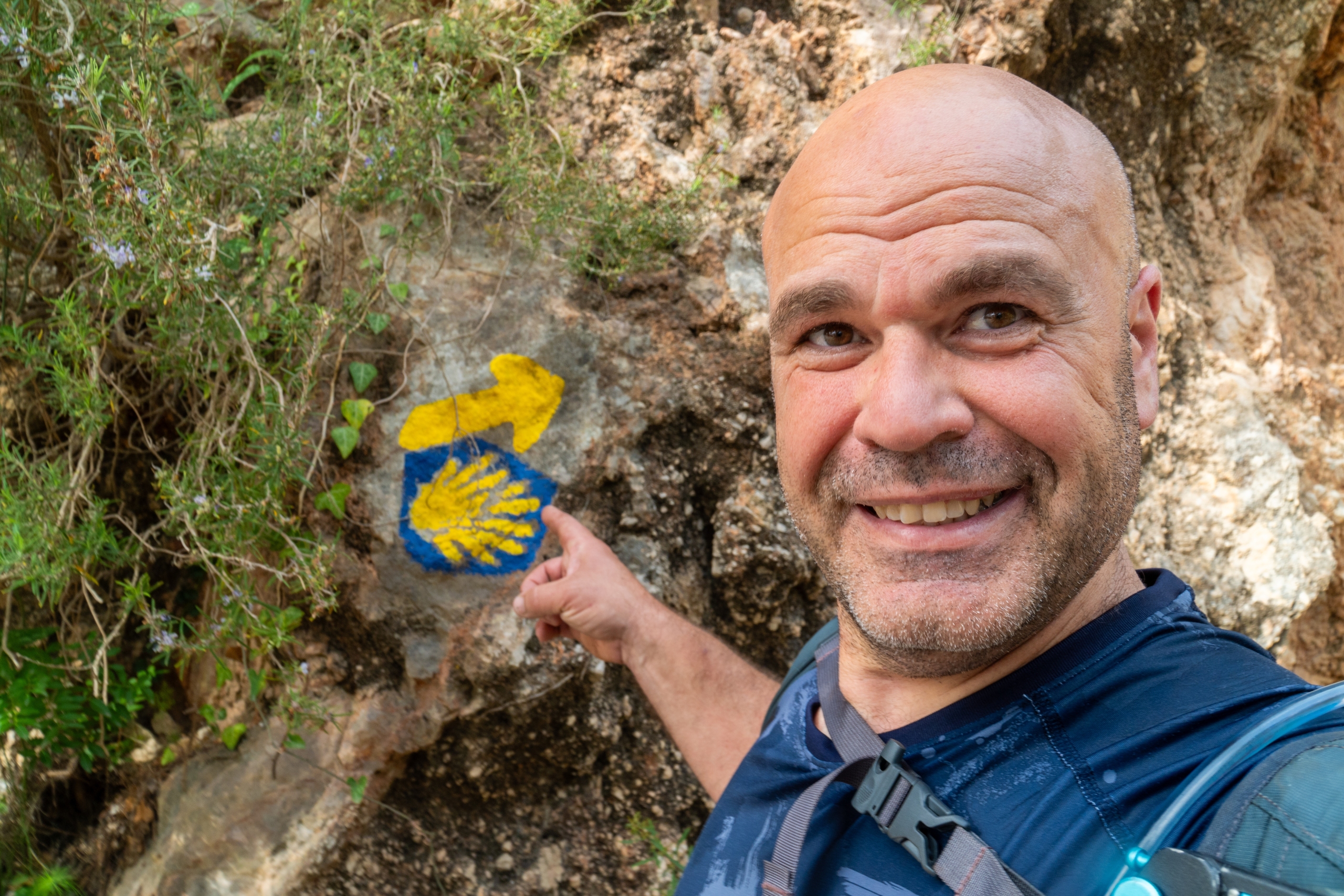 A pilgrim takes a selfie next to the symbols of the Camino de Santiago: the scallop shell and an arrow.